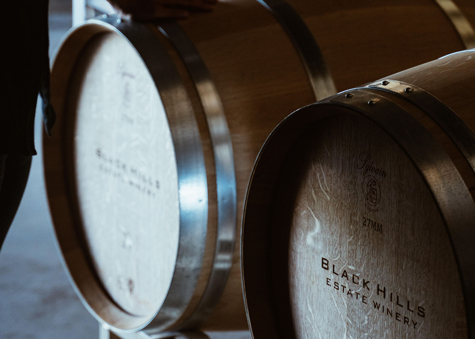 Close-up of two wooden wine barrels with metal bands, each marked with 